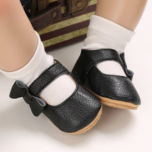 Load image into Gallery viewer, These charming little black bowknot baby shoes are perfect for babies aged newborn to 18 months old. With a choice of colors, they&#39;ll make a delightful addition to any outfit. A soft soled design ensures maximum comfort, while the bow-tie is sure to put a smile on everyone&#39;s face. Upper Material: PU Leather. Outsole Material: Rubber. Closure Type: Hook &amp; Loop.
